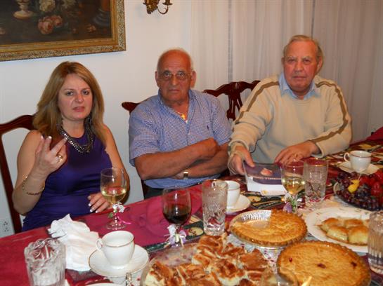 A group of people sitting at a table with food and wine glasses