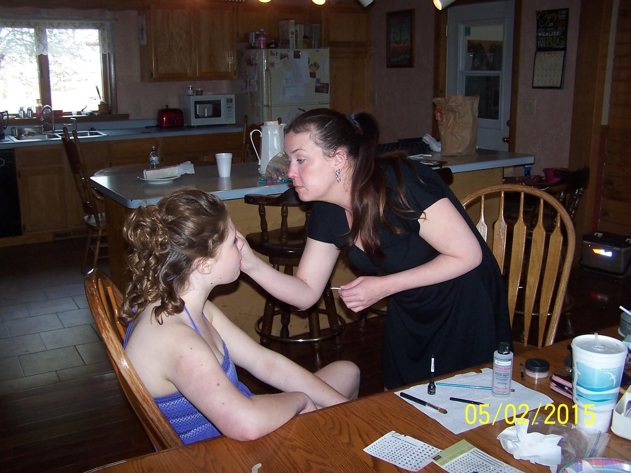 A woman putting makeup on a girl's face