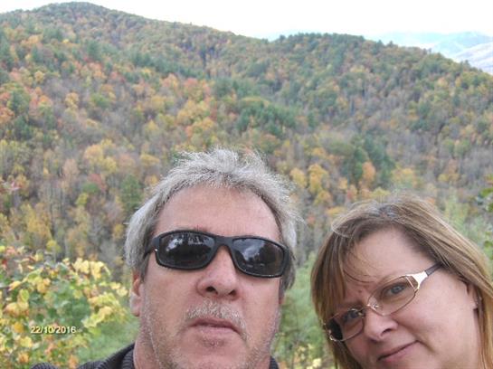 A man and woman taking a selfie in front of a forest