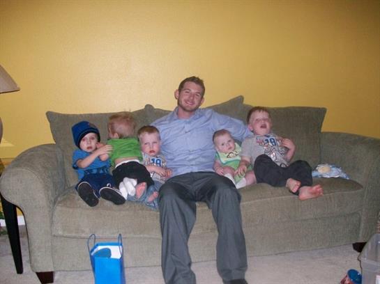 A man sitting on a couch with several babies