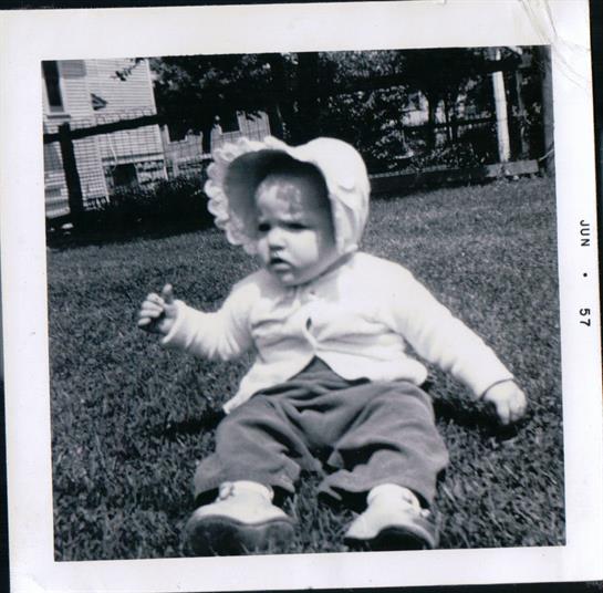 A baby sitting on grass