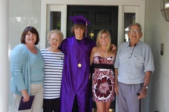 Family members gather to celebrate a graduation event in front of a house.