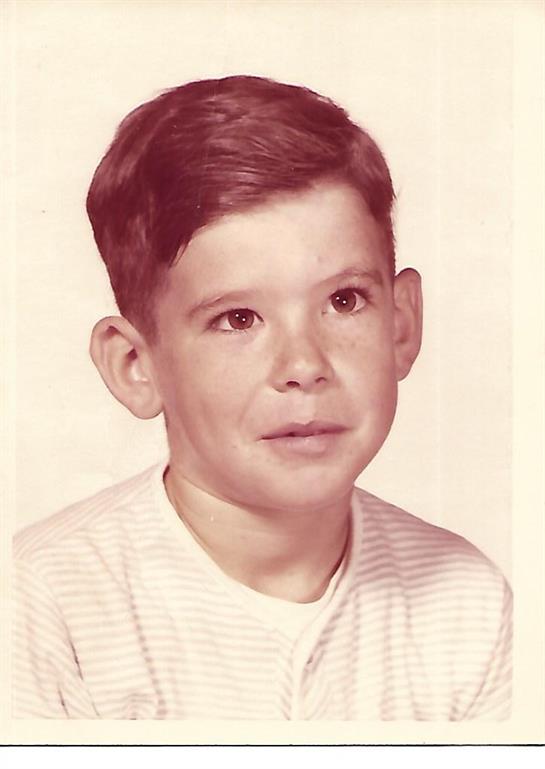 A boy poses for the camera with a serious expression while wearing a striped shirt.