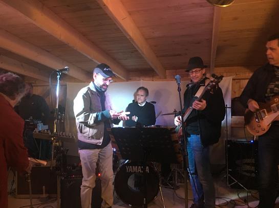 Musicians play lively tunes in an intimate wooden setting on a winter night.