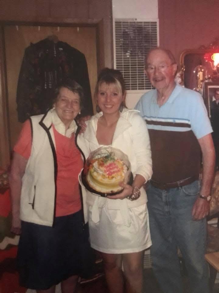 Friends and family come together to celebrate with a decorated cake in a warm home setting.