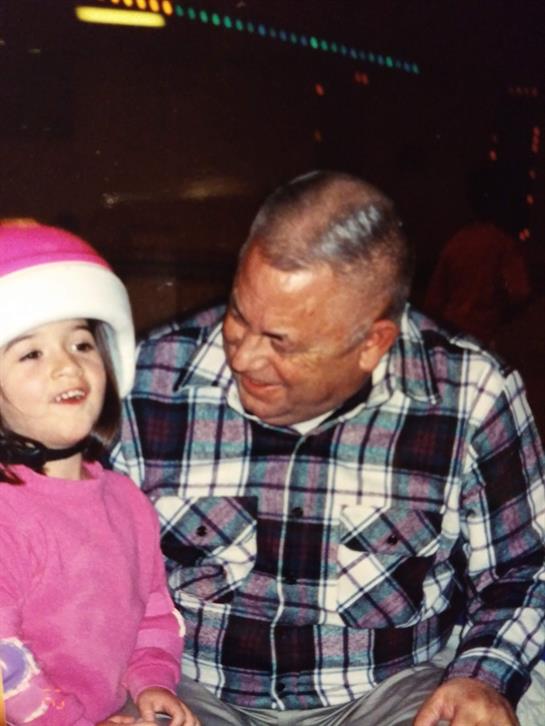 A happy grandfather smiles at his granddaughter as they share a light-hearted moment together.