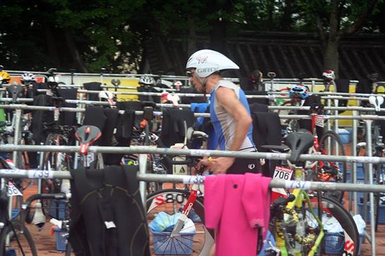 A cyclist organizes their bike among hundreds in a busy transition area at a competitive event.
