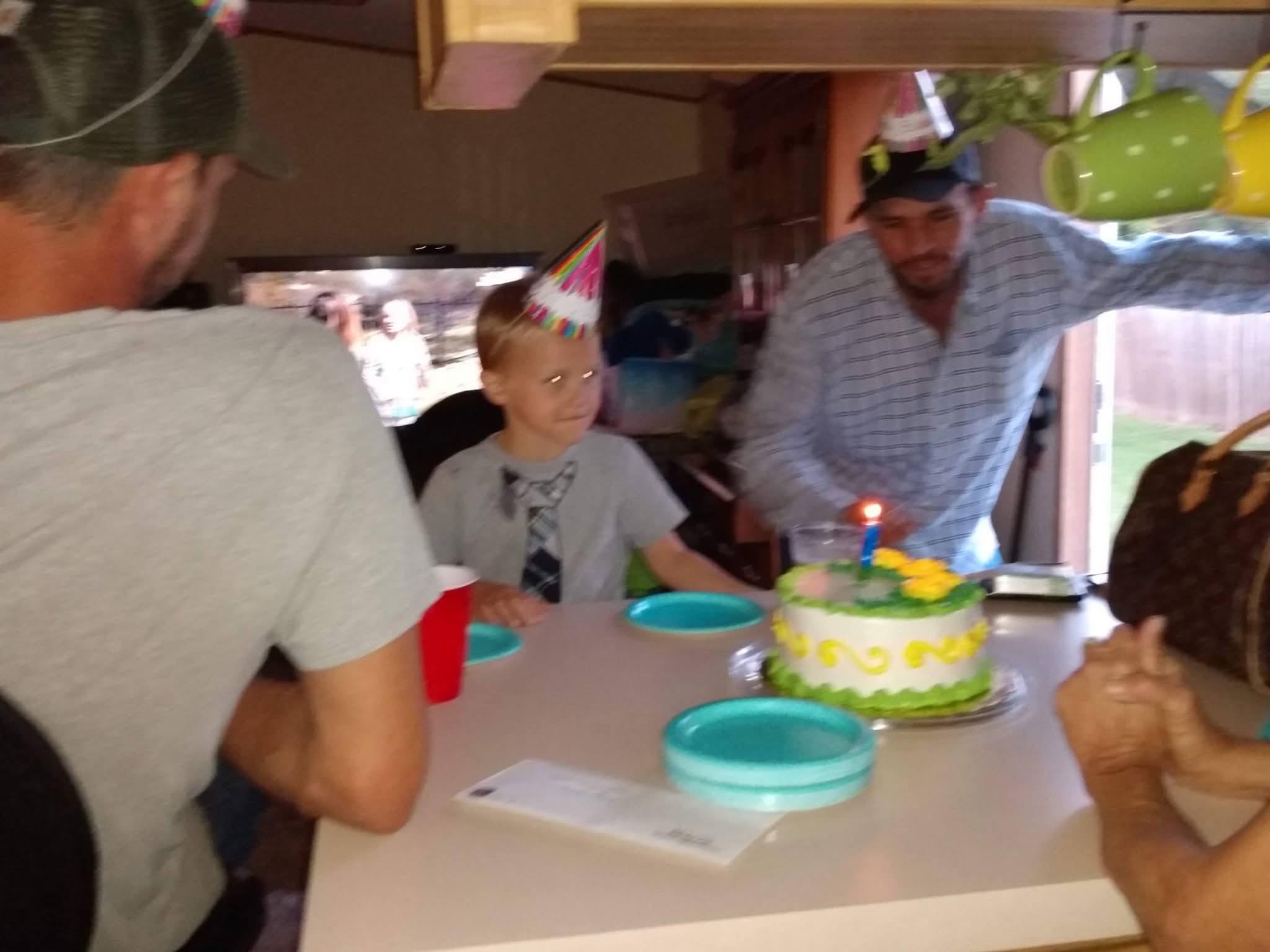 A group of people around a table with a cake and a birthday cake