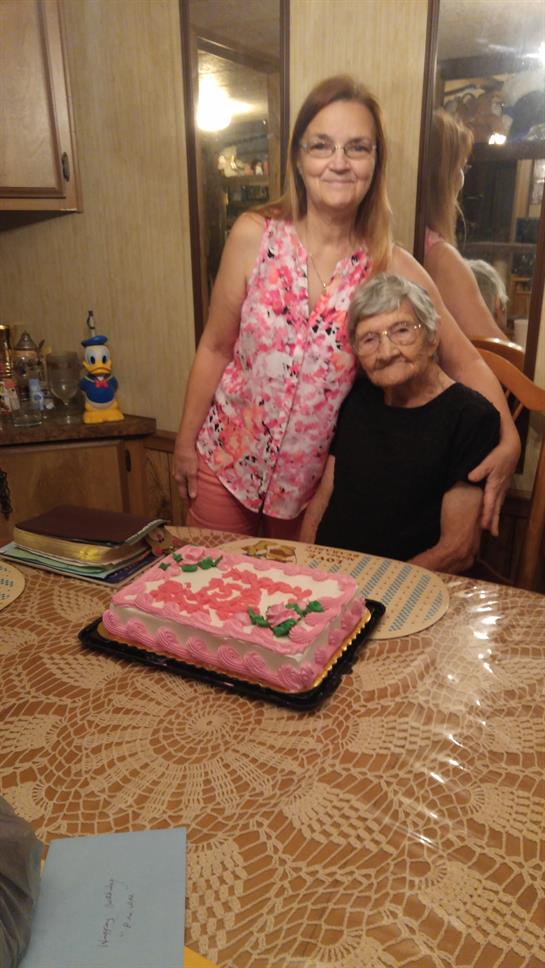 Two people are together in a home setting near a cake. They appear to share a special moment.