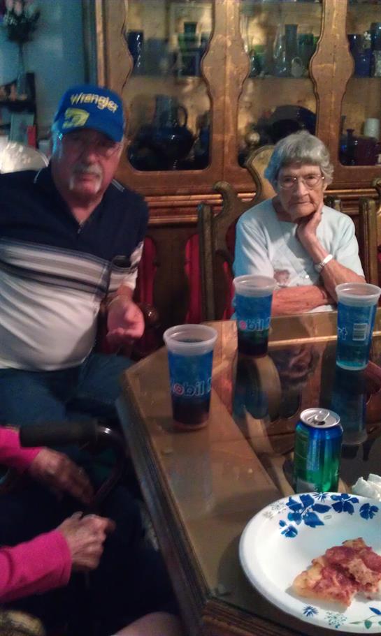 People sit at a table with drinks, talking and spending time together in a home setting.