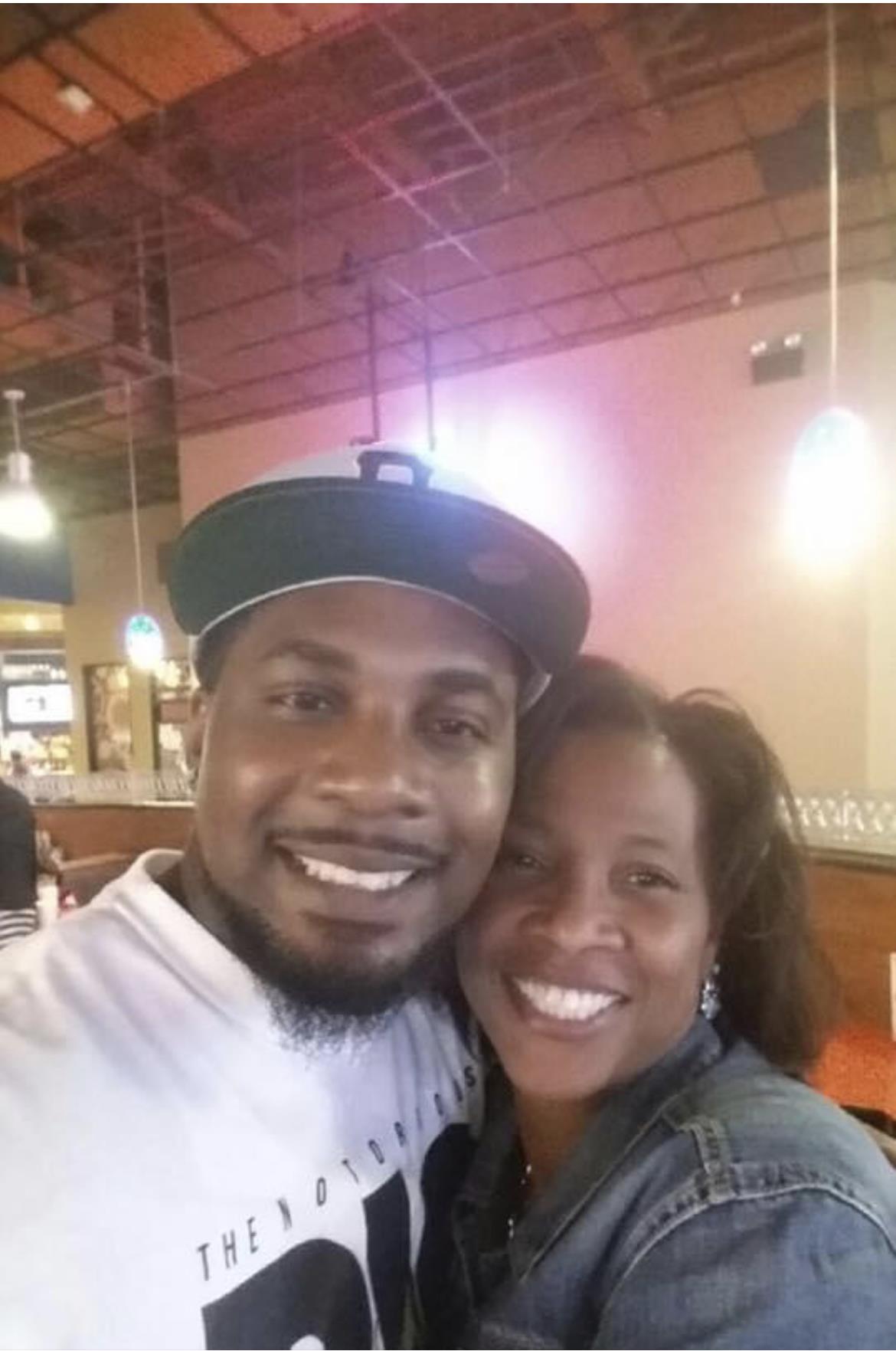 Two friends share a joyful moment together at a restaurant, smiling widely.