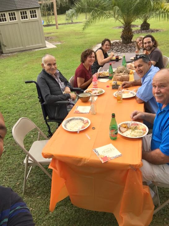 Friends and family enjoy a lively barbecue gathering at a vibrant table under the sun.