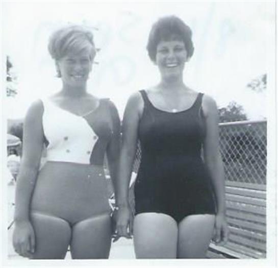 Two women stand together at a pool, smiling and wearing stylish swimsuits from the 1960s.