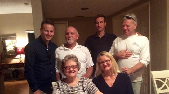 Relatives gather closely in a warm indoor space, smiling and enjoying each other's company.