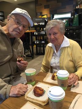 Couple shares freshly baked pastries and coffee while seated at a cozy cafe table.