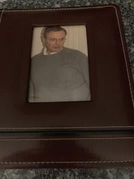 A framed family picture shows an older man in a gray sweater, smiling softly.