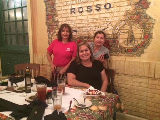 Three friends gather at a table, sharing laughter and delicious food in a charming restaurant.