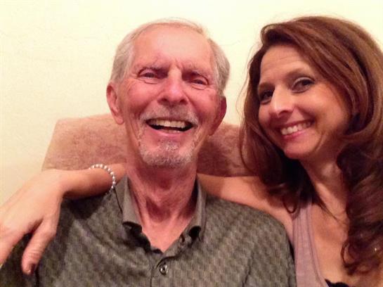 A senior man and a woman share a joyful moment, both laughing and smiling warmly together.