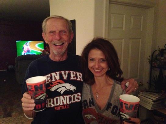 Two joyful fans hold drinks while displaying team spirit during a lively game night.