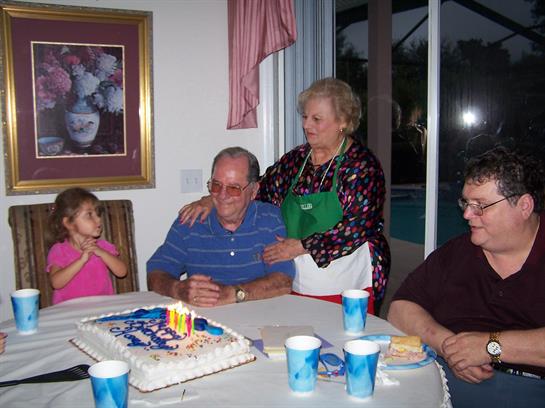 Family members celebrate a birthday with a decorated cake, laughter, and heartfelt moments captured.