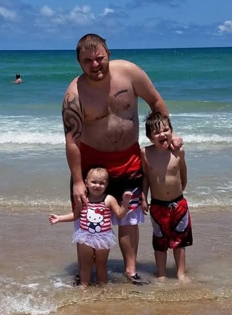 Children and their father play in the ocean, enjoying a warm day at the beach with laughter.