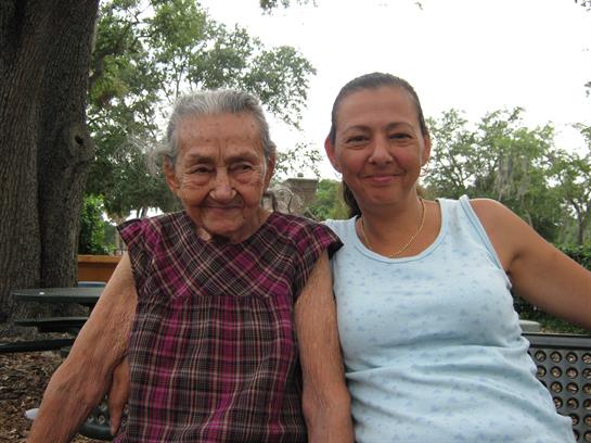 Two generations smile together in a park, enjoying the warmth of a summer afternoon with nature.