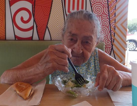 Senior woman savors her meal at a lively cafe with artistic decor during lunchtime.