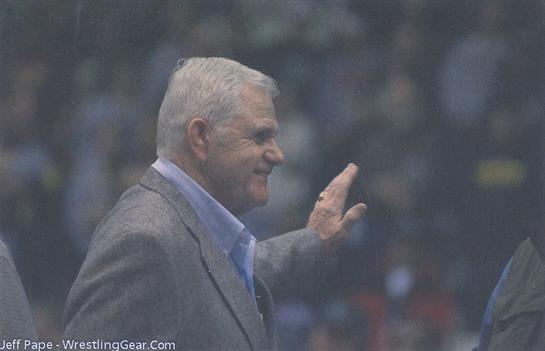 Coach greets the cheering crowd with a wave, showing appreciation for their support.