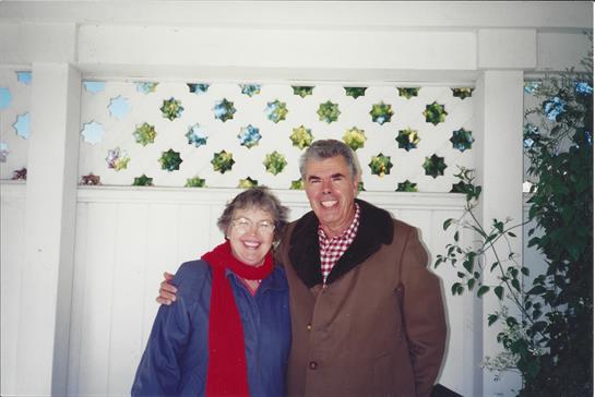 Two cheerful individuals pose with friendly smiles in a colorful interior, showcasing their warmth.