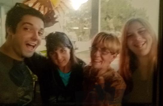 Four friends share laughter and smiles at a casual outdoor gathering on a sunny day.