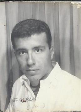 A man with dark hair and a serious expression poses, showcasing classic mid-century style.