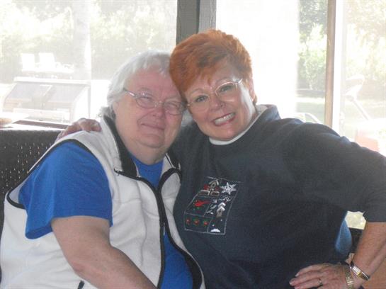 Two friends share a warm embrace and smile while sitting in a comfortable cafe.