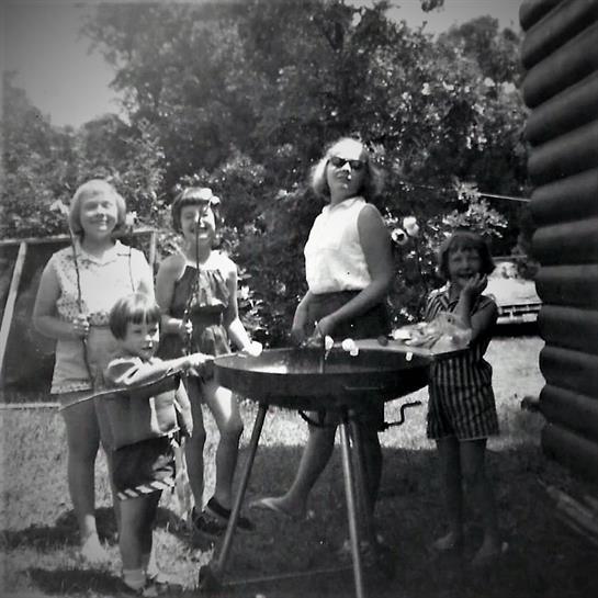 Family enjoying a summer barbecue in their backyard with smiles and laughter on a sunny day.