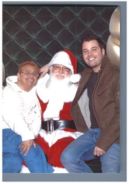 Two joyful adults sit beside Santa Claus, posing for a cheerful holiday moment during a celebration.