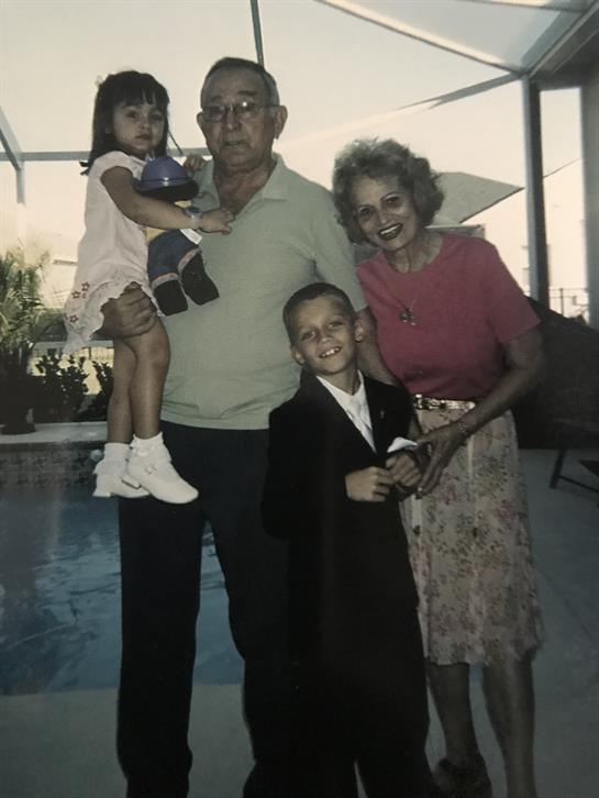 A joyful family stands together by a pool, smiling and enjoying a sunny afternoon.