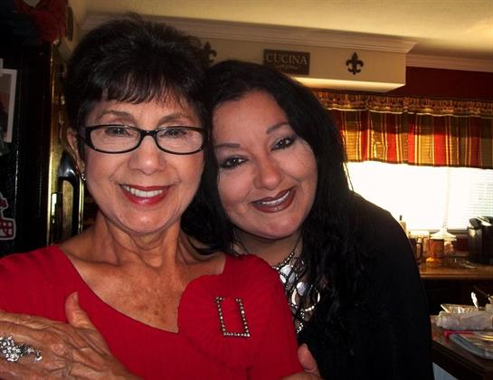 Two women smile brightly in a kitchen, enjoying a family gathering filled with love and happiness.