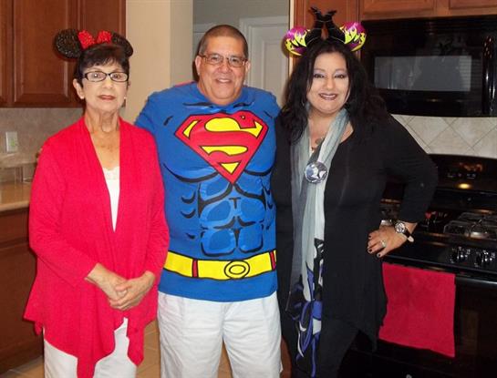 Three friends enjoy a festive gathering in a warm kitchen, each wearing colorful costumes.