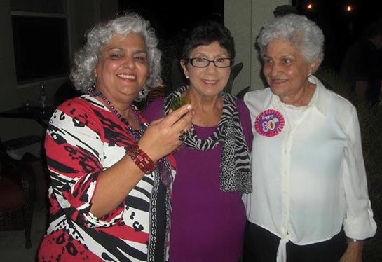 Three women smile and pose with excitement during a celebration, creating a joyful atmosphere.