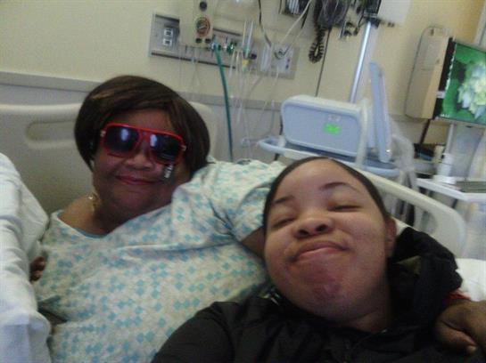 Two family members share smiles in a hospital, showing love and support during recovery.