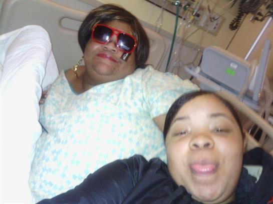 Two women enjoy a lighthearted moment in a hospital setting, wearing sunglasses and smiling.