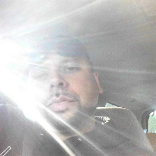 A man sits in a car, engaging with the camera while sunlight filters in, creating a bright effect.