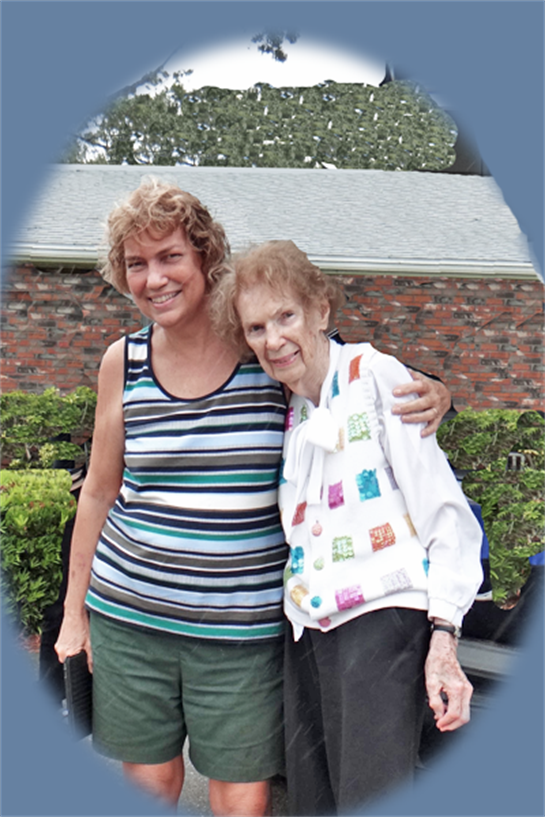 Two women embrace happily in front of a lovely garden, enjoying the warm day together.