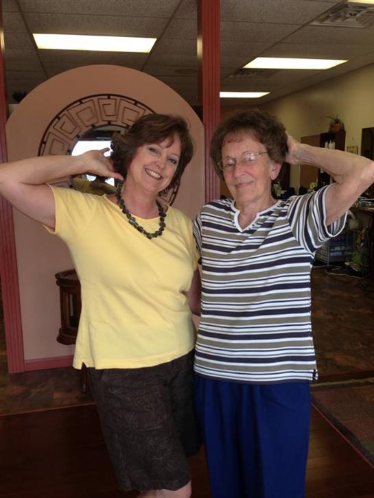 Two women are happily posing together with smiles in a relaxed indoor atmosphere.