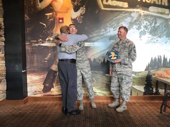Two soldiers embrace a family member in an emotional moment during a farewell gathering.