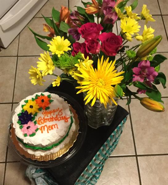 A decorated cake and vibrant flowers celebrate a birthday in the kitchen.