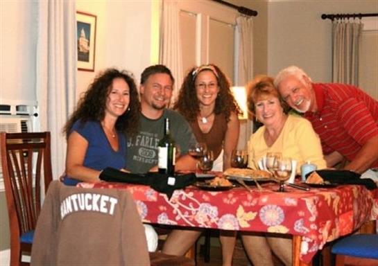 Group of friends gathered at a table, enjoying dinner and each other's company with wine.