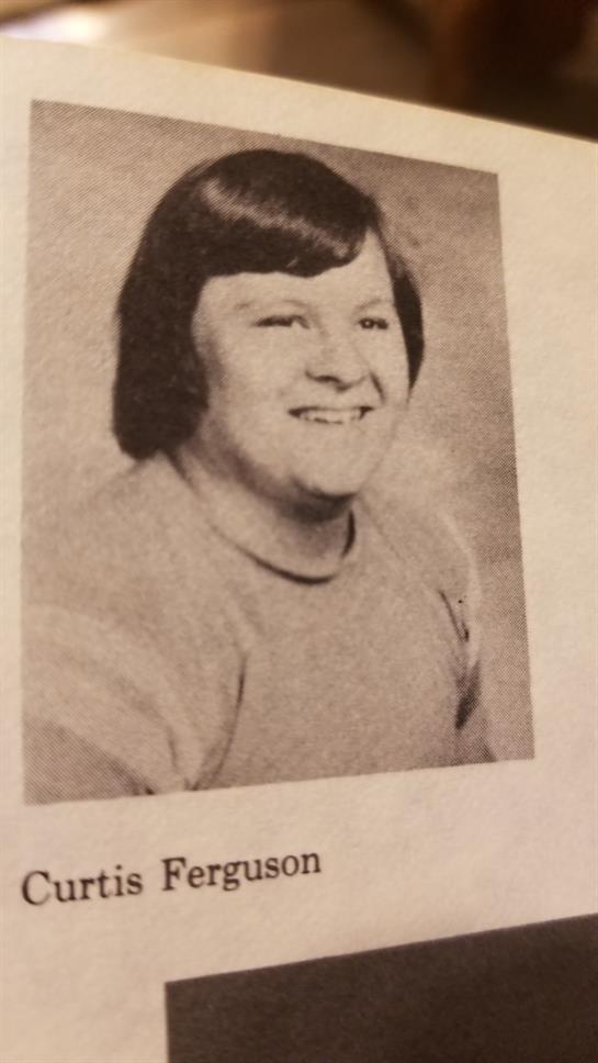 A young girl with shoulder-length hair smiles brightly while wearing a casual sweater.