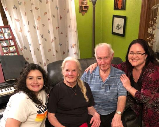Four family members sit closely together, smiling in a well-decorated living room full of memories.