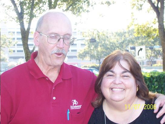 Two friends stand closely in a park, laughing and enjoying each other's company on a sunny day.