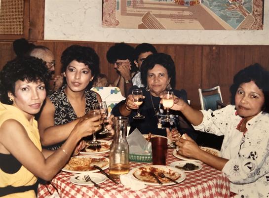 Friends enjoying a lively gathering at a restaurant, raising glasses and sharing delicious food.